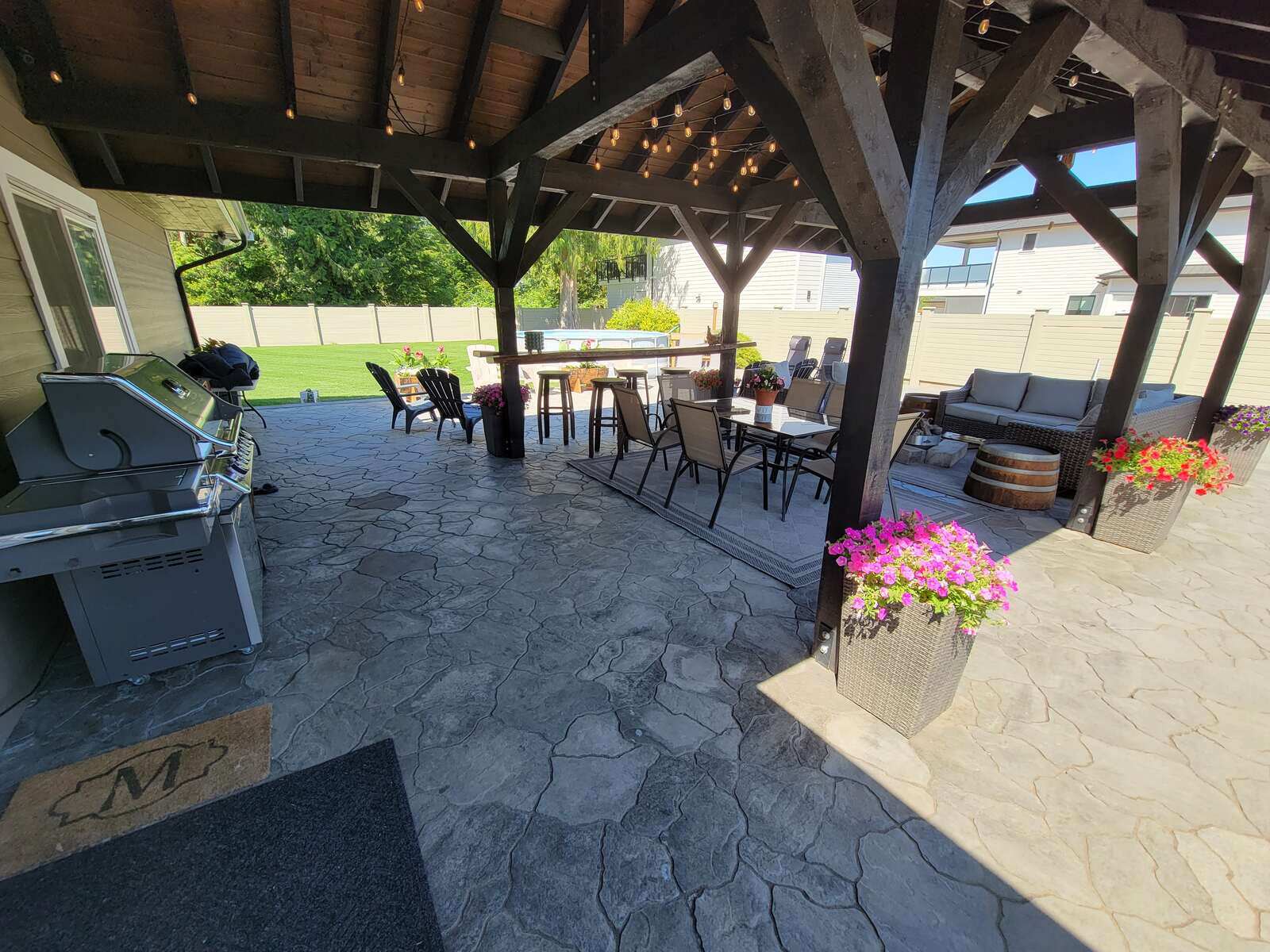 Stone wall and seating area under pergola by Back 40 Landscaping in Abbotsford, BC