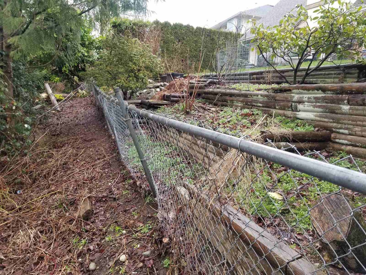 1_Damaged chain-link fence along a sloped yard before landscaping improvements by Back40 Landscaping in Abbotsford, BC