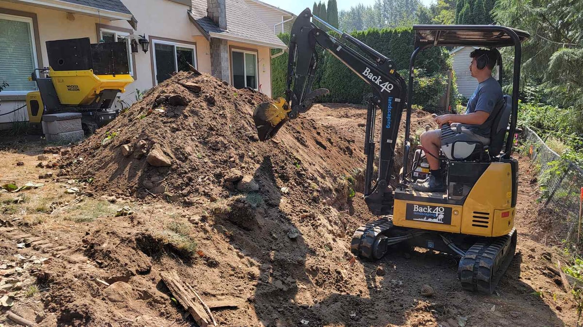 4_Mini excavator digging soil next to a home for a landscaping transformation by Back40 Landscaping in Abbotsford, BC
