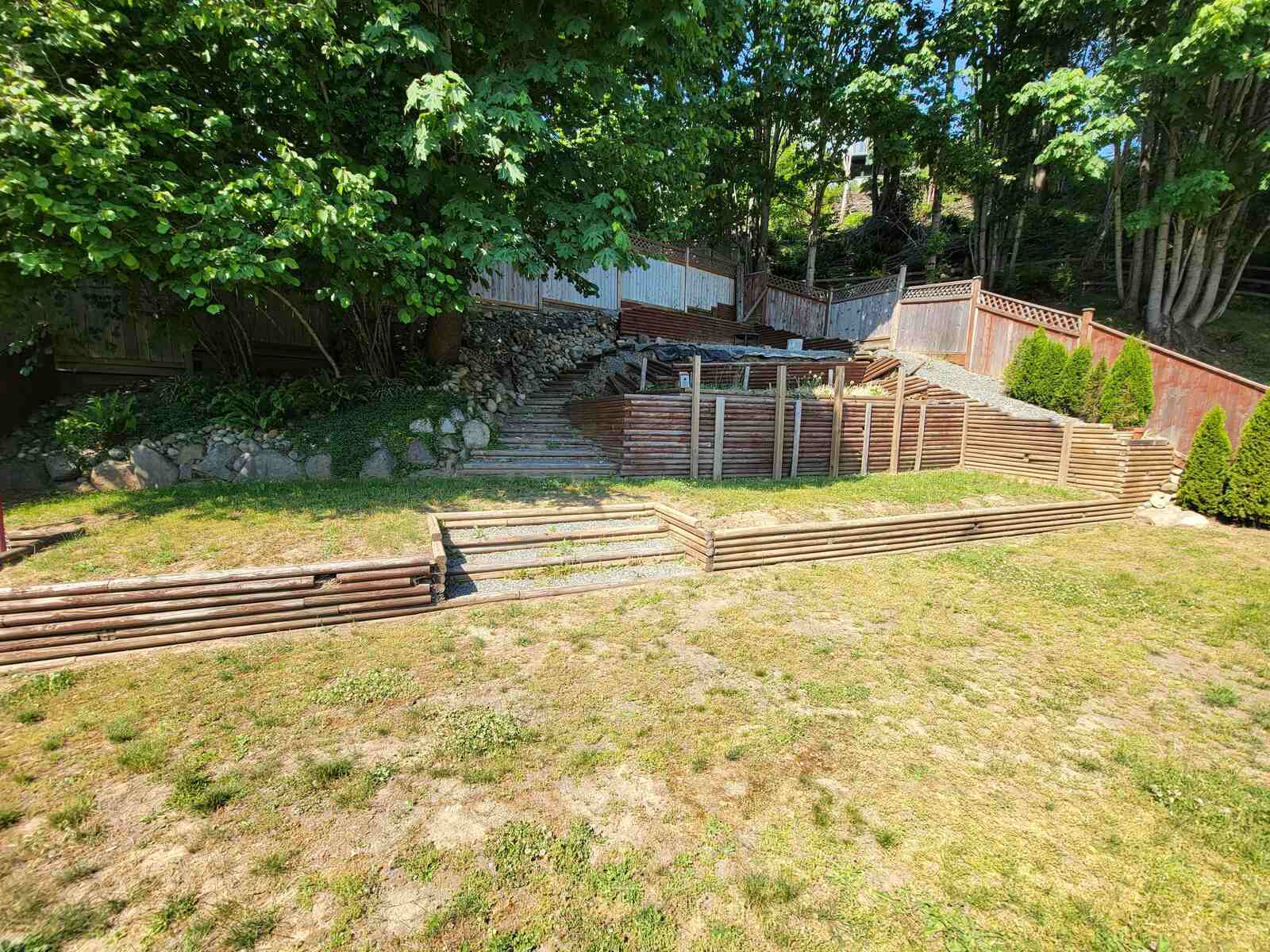 2_Progress on a four-tiered retaining wall by Back40 Landscaping in Mission, BC, showcasing wooden terraces in a backyard setting