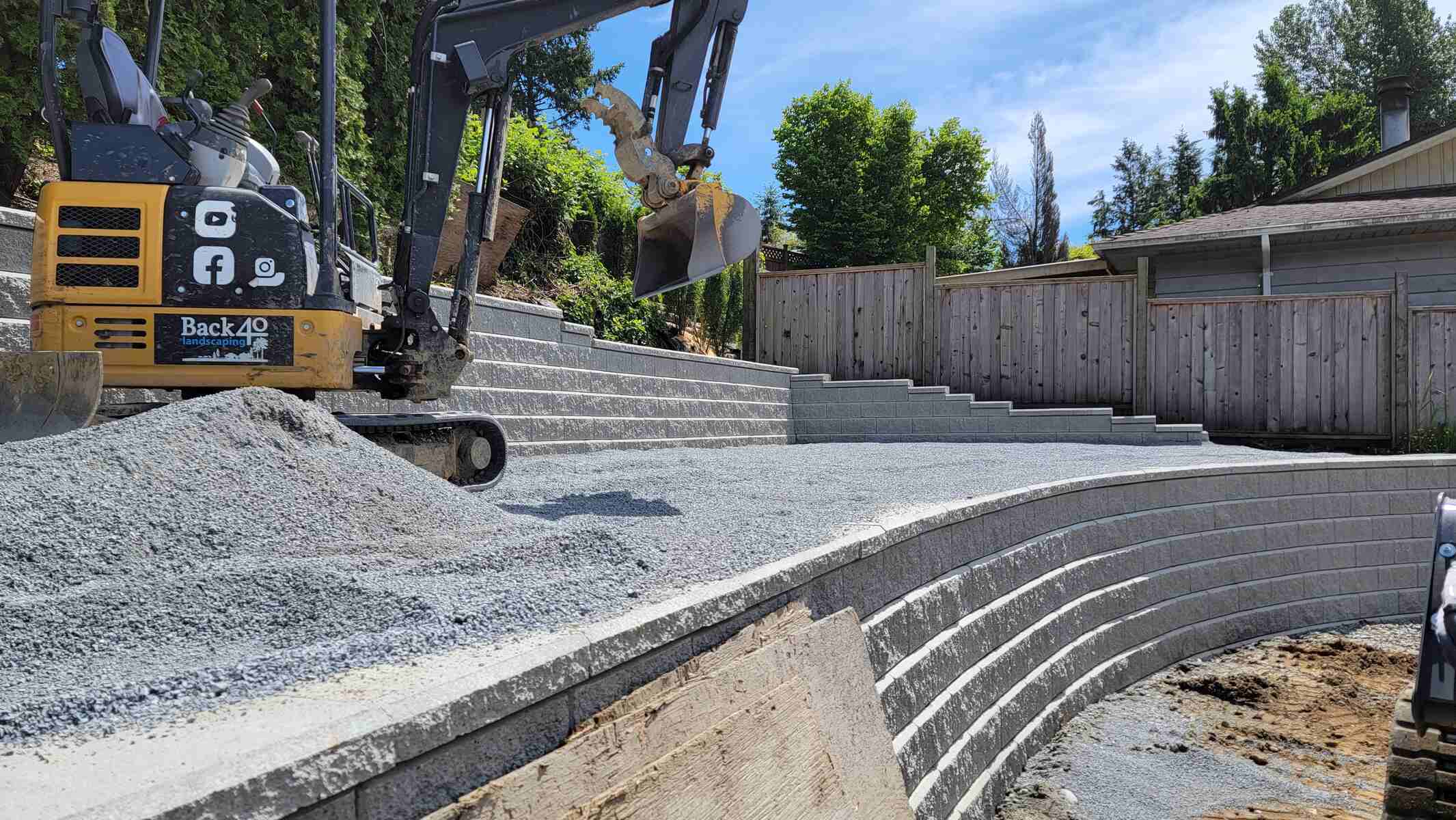 11_Excavator spreading gravel over a newly constructed retaining wall by Back40 Landscaping in Mission, BC