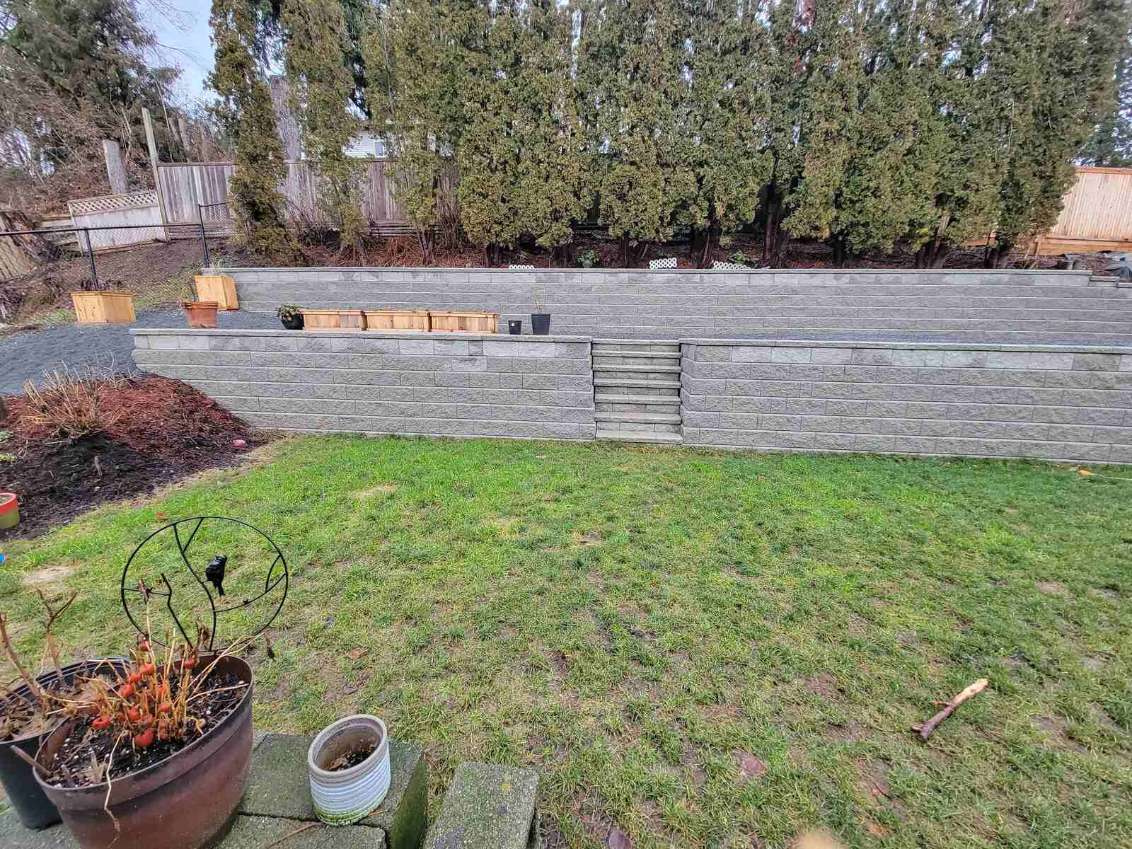 18_Stone retaining wall with built-in steps in a landscaped backyard by Back40 Landscaping in Mission, BC