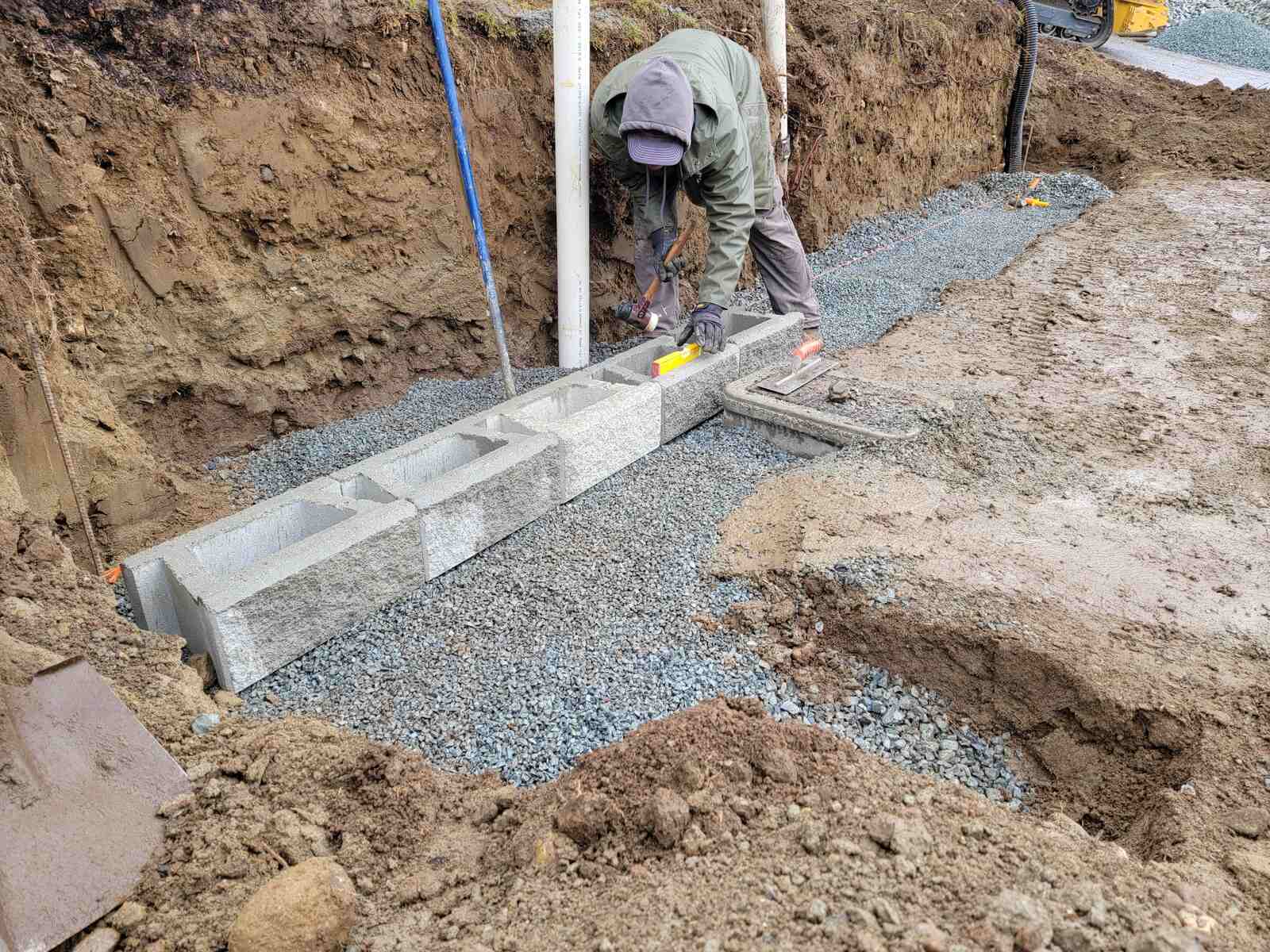 10_Worker constructing a concrete block retaining wall foundation in Mission, BC, for Back40 Landscaping