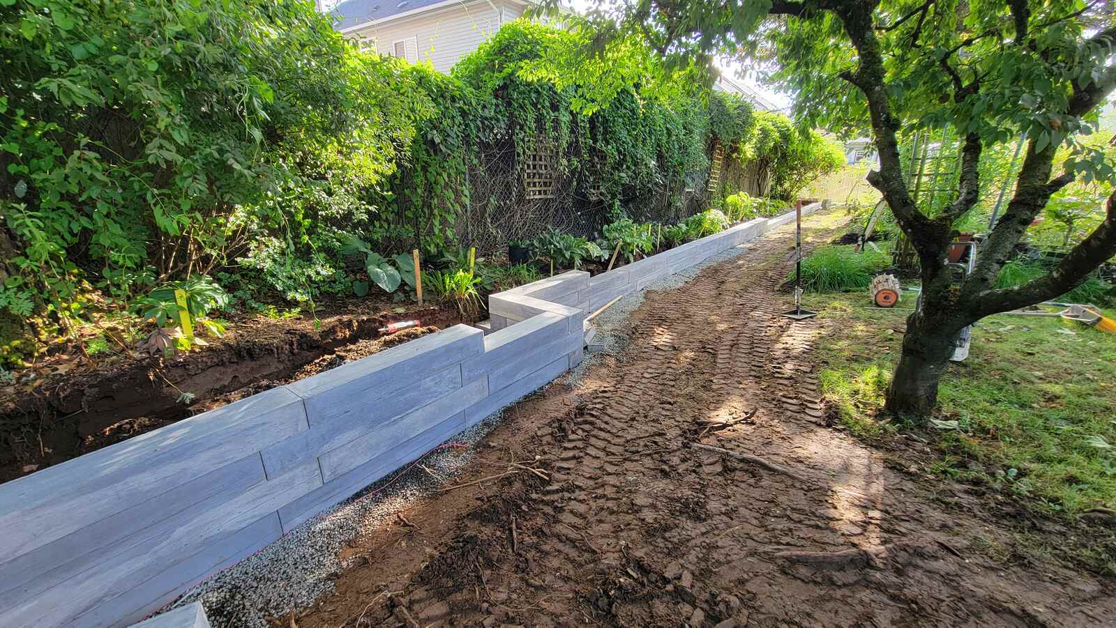 Freshly installed concrete retaining wall with wood texture along garden bed by Back 40 Landscaping in Abbotsford, BC