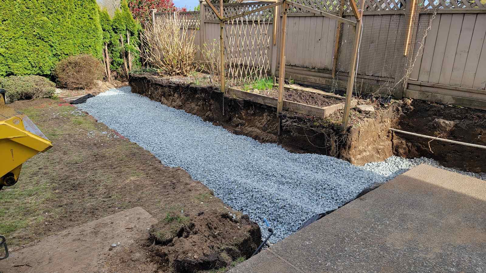 Excavated garden area with gravel foundation for retaining wall installation by Back 40 Landscaping in Burnaby, BC