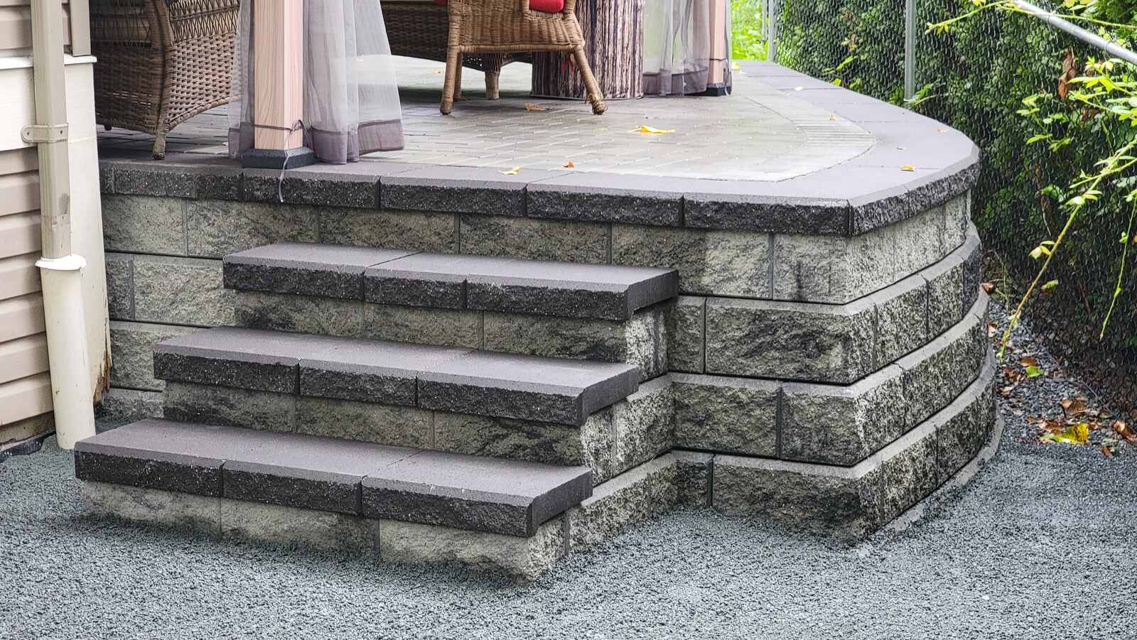 Close-up of custom stone steps leading to elevated patio by Back 40 Landscaping, Chilliwack, BC