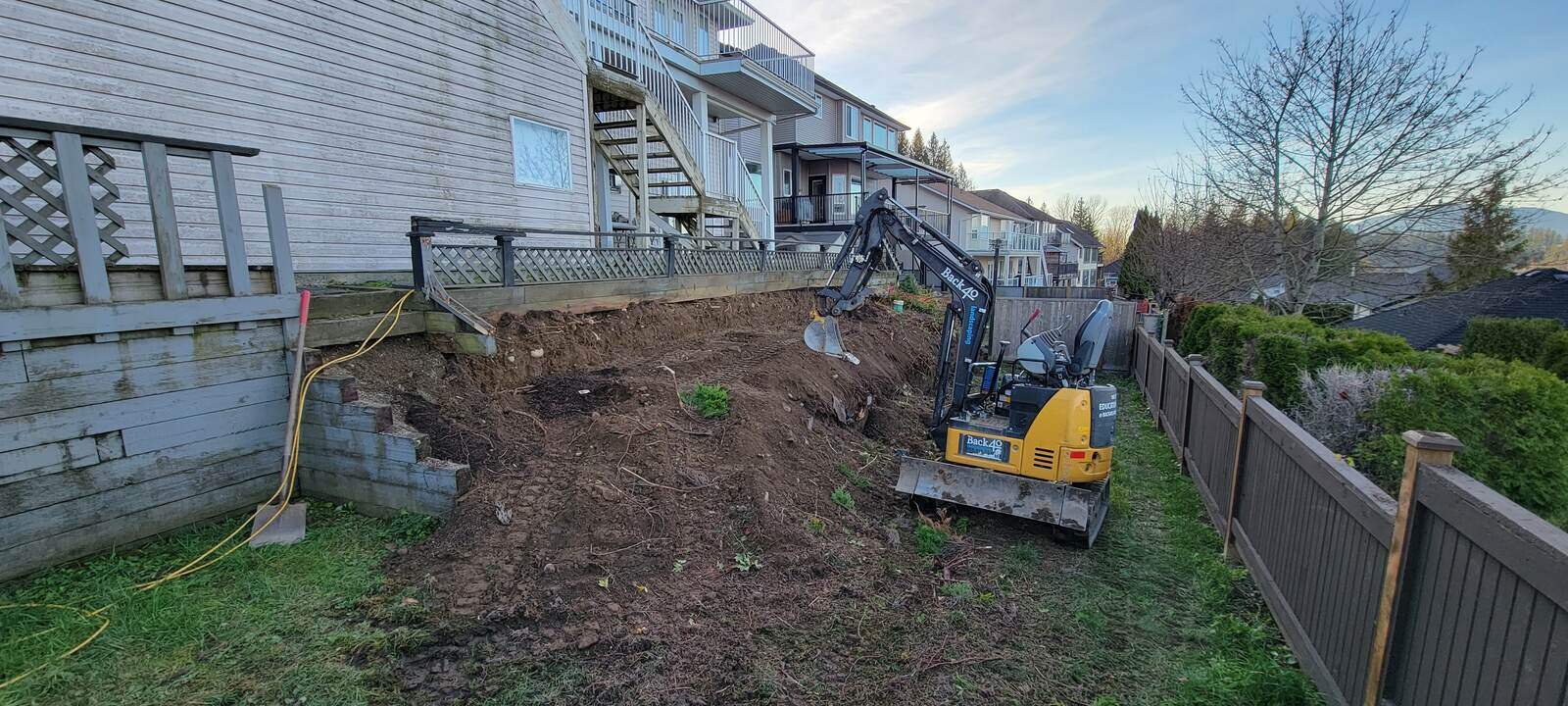 Excavator removing soil for retaining wall construction by Back 40 Landscaping in Chilliwack, BC