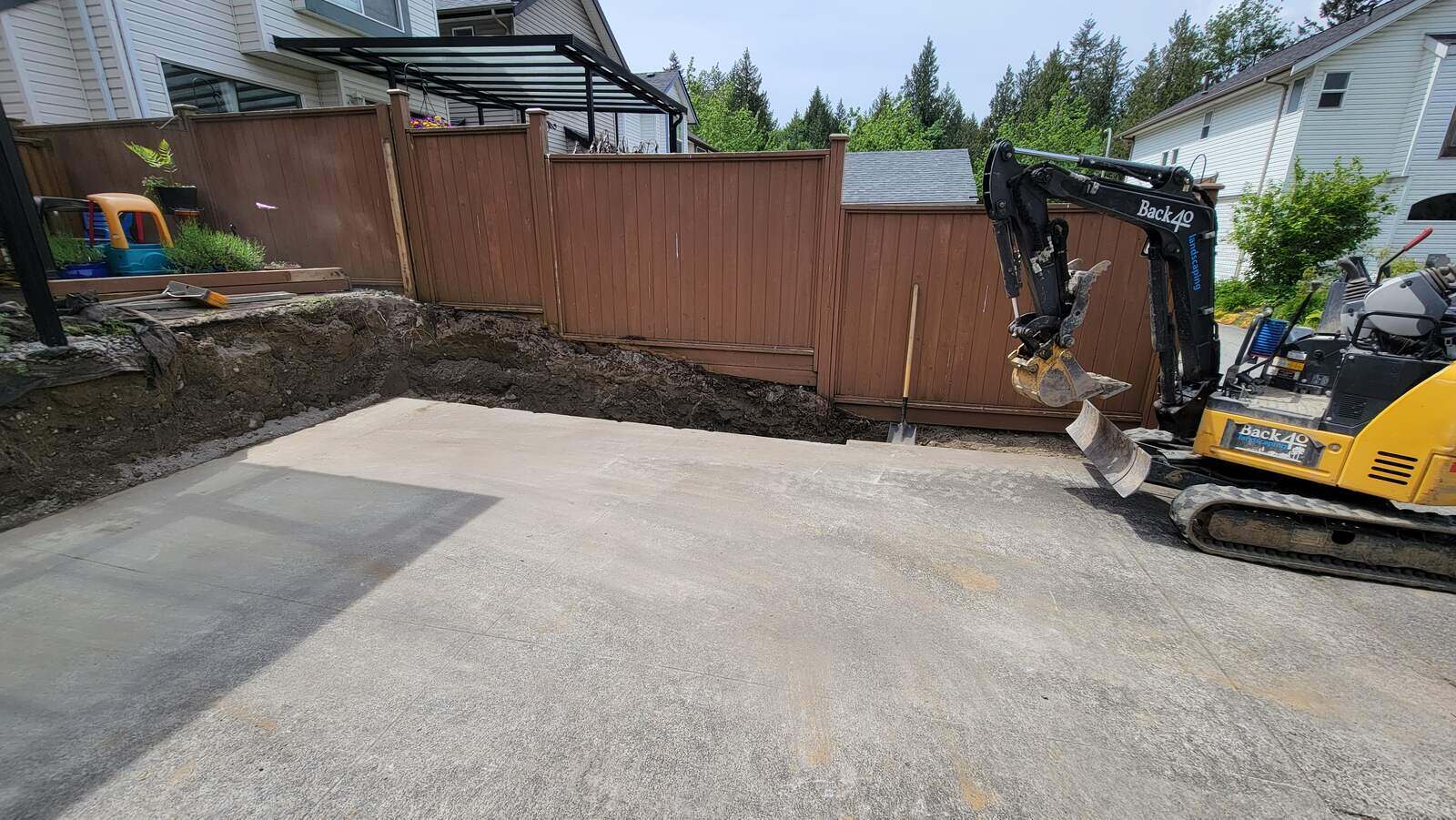 Excavator preparing for backyard retaining wall rebuild in Langley, BC by Back 40 Landscaping