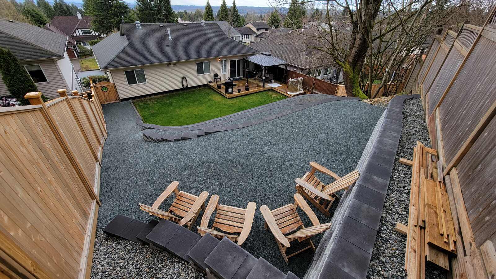 Patio seating area beside a multi-tier retaining wall in Langley, BC by Back 40 Landscaping