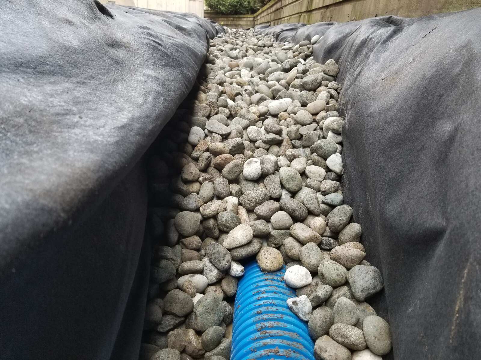 Close-up of a drainage trench with gravel and pipe installation by Back 40 Landscaping in Abbotsford, BC