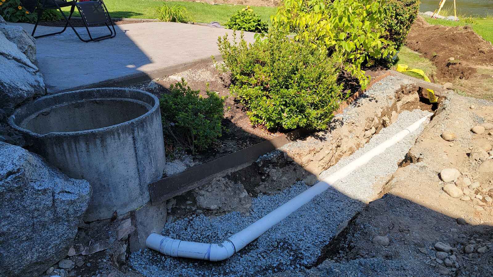 Drainage pipe installation in gravel near patio by Back 40 Landscaping in Abbotsford, BC