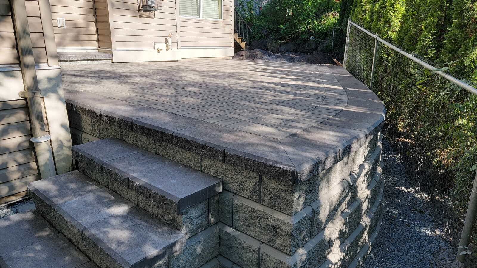 Elevated stone patio by Back 40 Landscaping in Abbotsford, BC, showcasing layered stonework and steps