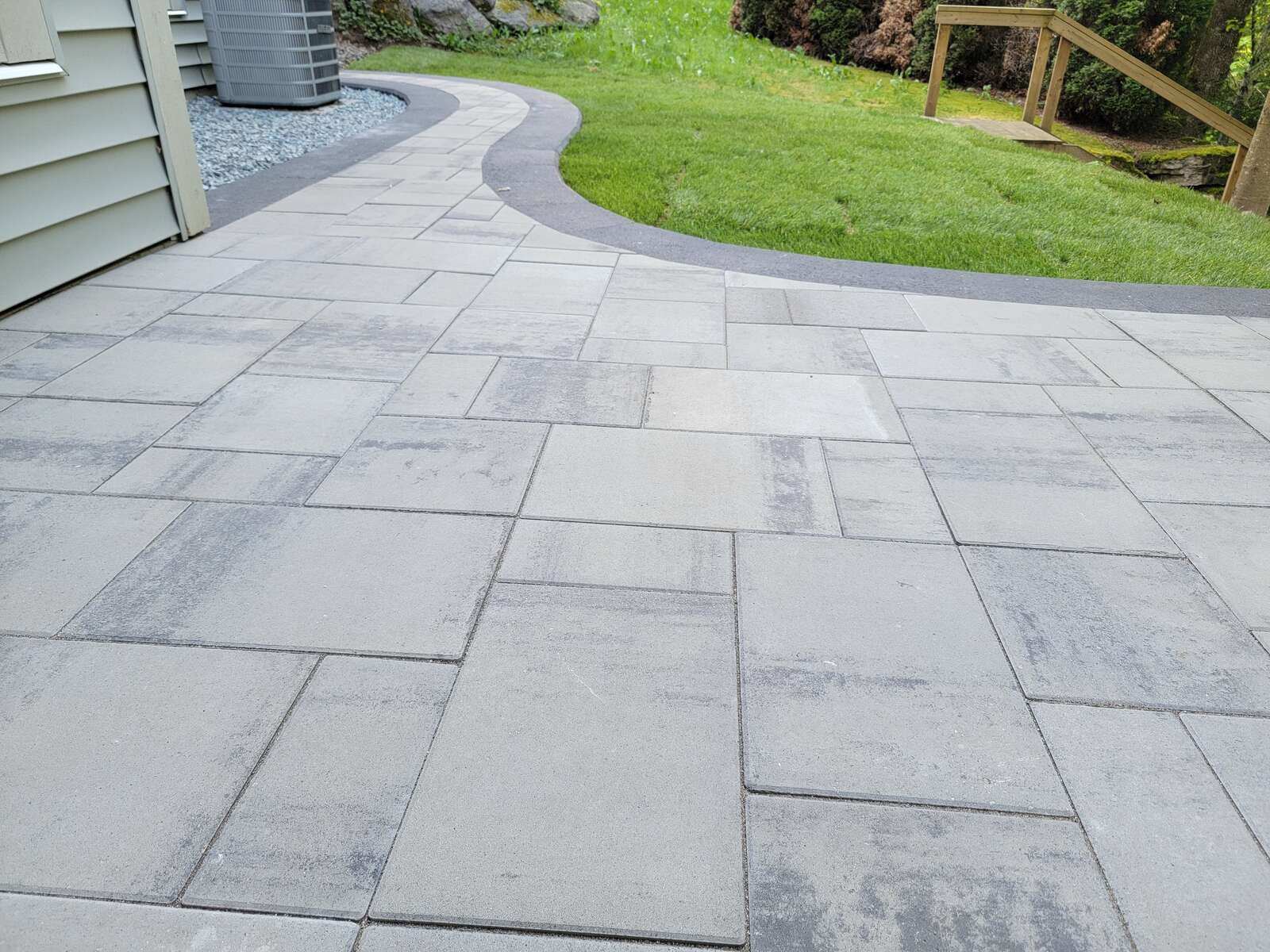 Sleek stone patio adjacent to a landscaped lawn by Back 40 Landscaping, Abbotsford, BC