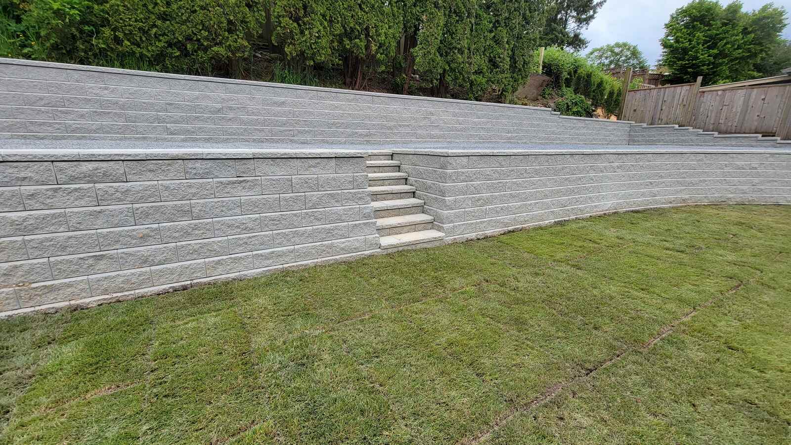 Large, curved retaining wall with layered stone design by Back 40 Landscaping in Abbotsford, BC