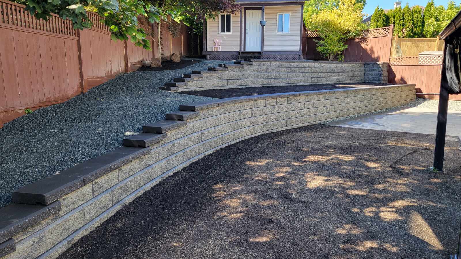 Multi-level retaining wall with curved design and gravel by Back 40 Landscaping in Abbotsford, BC